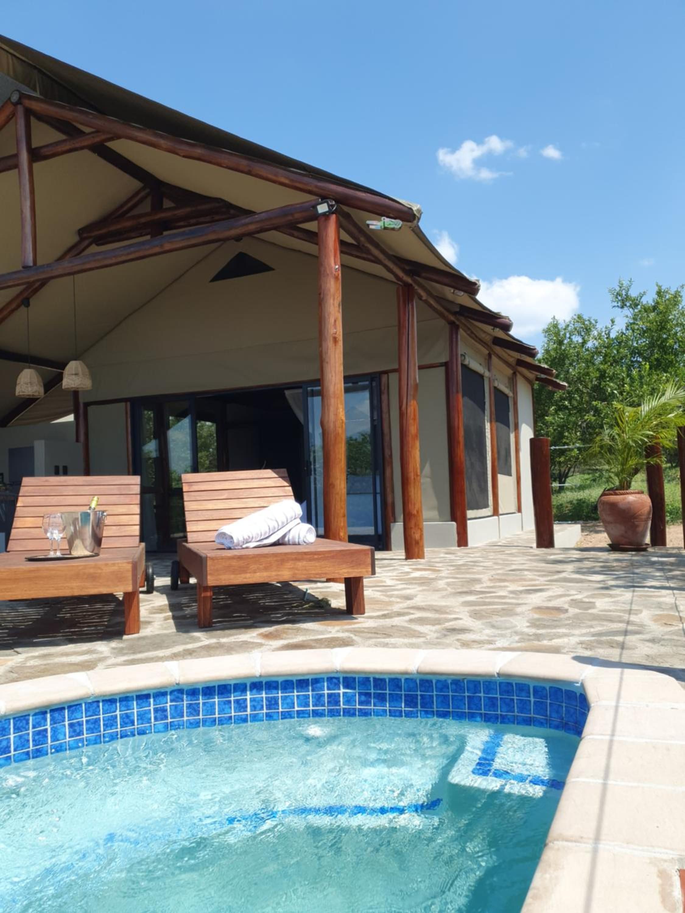 Un espace piscine avec des chaises longues et un patio couvert.