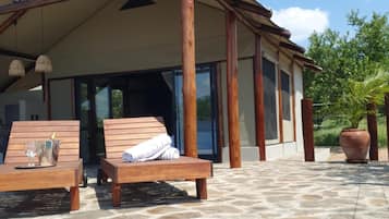 Un espace piscine avec des chaises longues et un patio couvert.