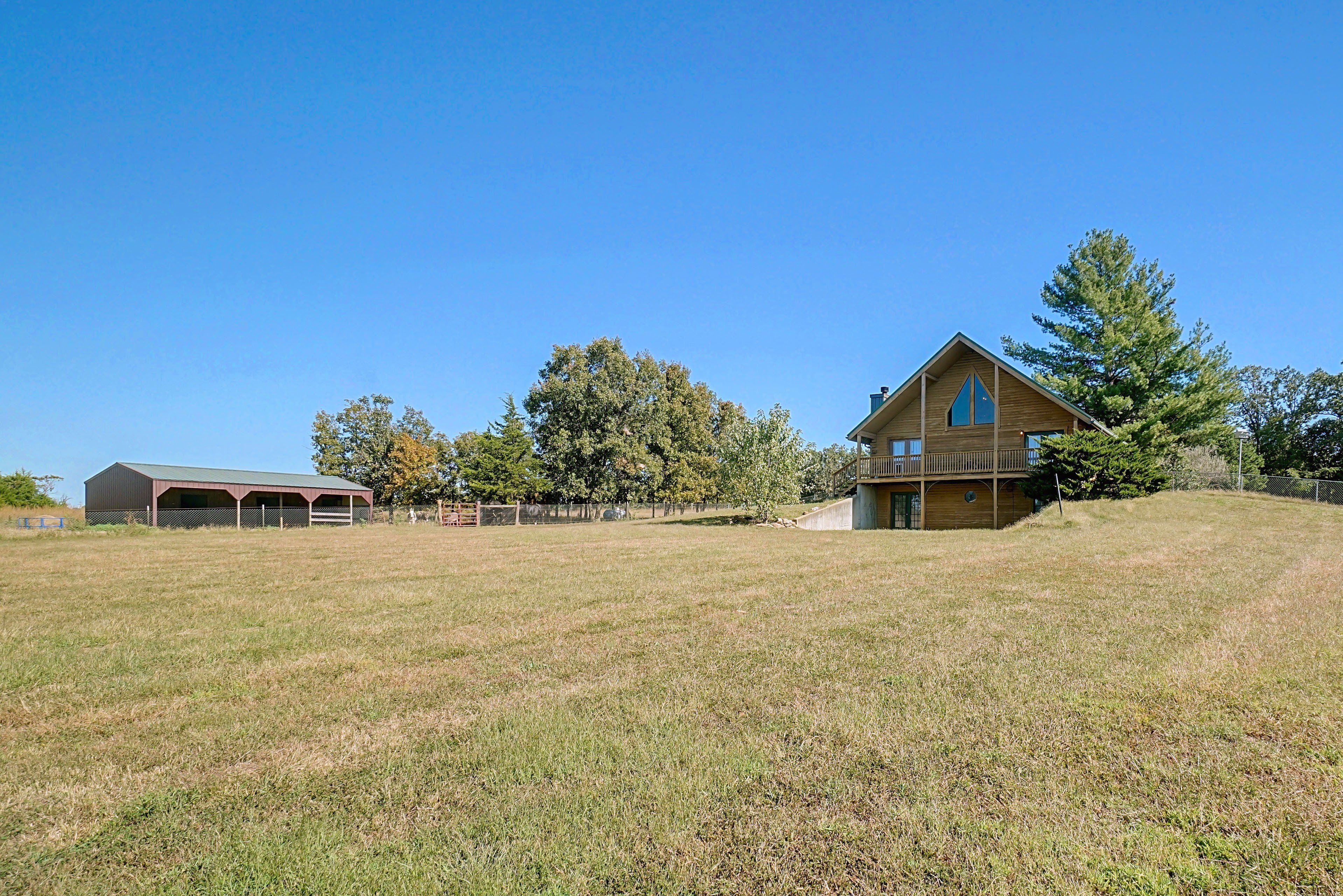 A two-story wooden house with a large front porch and a fenced yard.