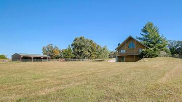 A two-story wooden house with a large front porch and a fenced yard.