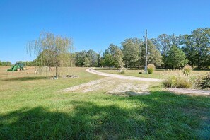 Ländliche Landschaft mit Feldweg, grünem Gras und Bäumen.