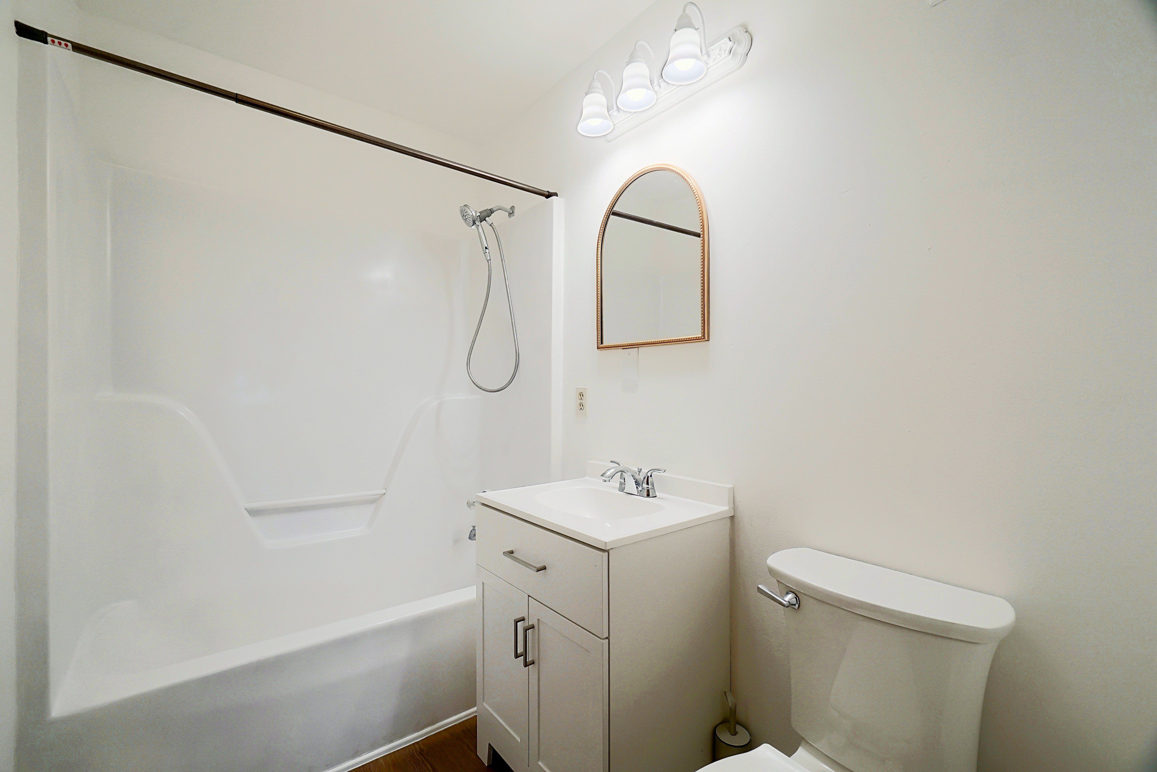A bathroom with a bathtub, a sink, a toilet, and a mirror.