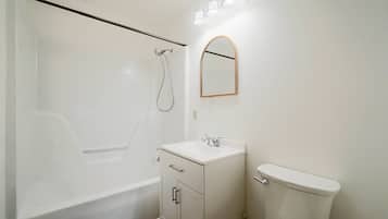 A bathroom with a bathtub, a sink, a toilet, and a mirror.