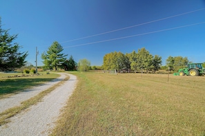 A rural landscape with a gravel path, trees, and a green tractor.
