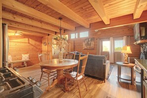 Un interior de madera con una mesa de comedor, sillas, un sofá y una zona de cocina.