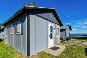 A small, single-story building with a sloped roof, a door, and windows. - Direct Shoreline Access! Tawas City Cabin (Tawas City)