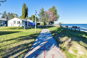 A clear path leading to a beach with a swing set and a small building. - Direct Shoreline Access! Tawas City Cabin (Tawas City)