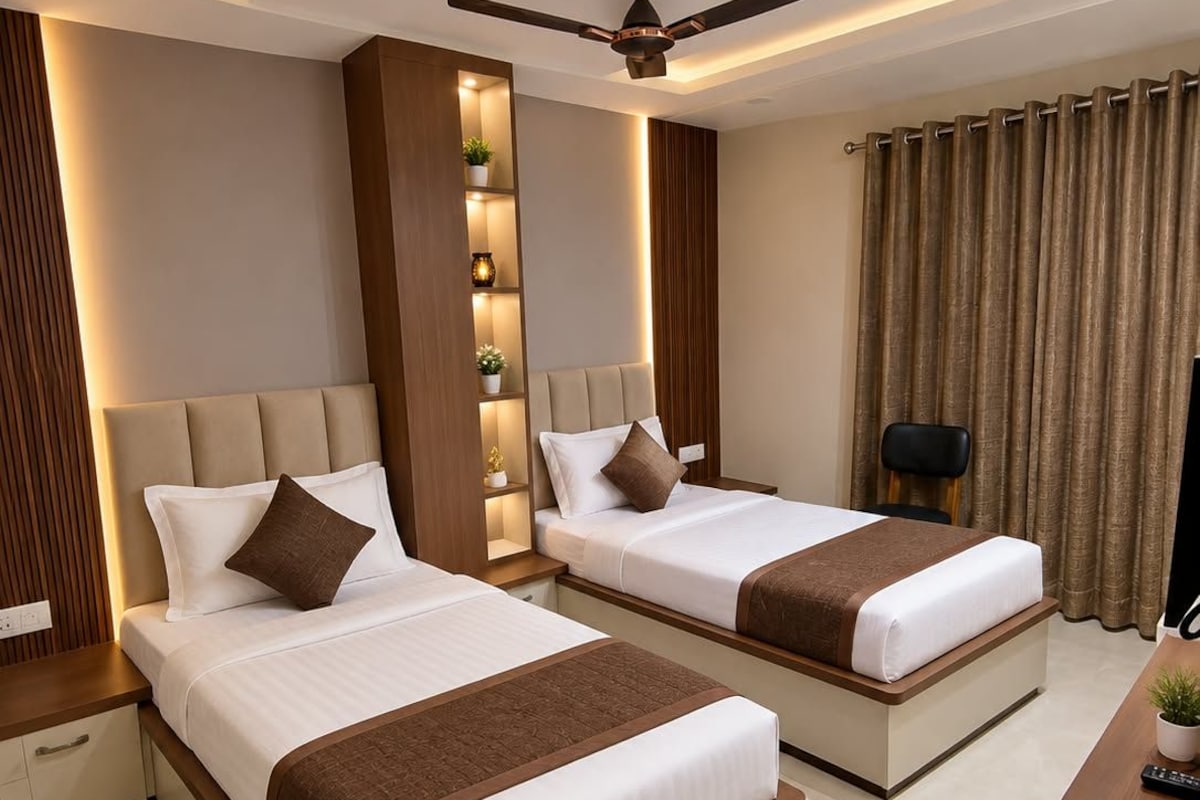 A hotel room with two beds, a ceiling fan, recessed lighting, a nightstand, a desk, and a window with curtains.