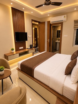 A modern bedroom with a large bed, a flat-screen TV, a ceiling fan, and a built-in air conditioning unit. - Hotel Empire Inn  (Varanasi)