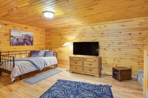 A wooden cabin room with a bed, a television, a dresser, and a rug. - Rustic Cabin Retreat in the Peaceful Mountains (Elk Park)