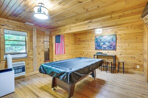 A wooden cabin interior with a table, chairs, an American flag, and a painting on the wall. - Rustic Cabin Retreat in the Peaceful Mountains (Elk Park)