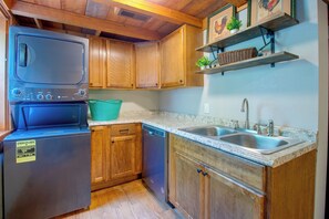 A compact kitchen with wooden cabinets, a built-in dishwasher, and a double sink. - Norfork Lake Cabin, 2 Mi to the Water (Jordan)