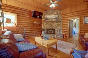 A log cabin interior with a stone fireplace, leather furniture, and a ceiling fan. - Norfork Lake Cabin, 2 Mi to the Water (Jordan)
