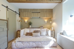 A bedroom with a bed, bedside tables, wall-mounted lamps, and a window. - Mid-Century Modern Chateau du Coach House (Iowa City)