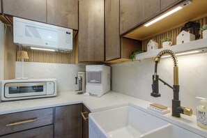 Una cocina moderna con microondas, cafetera y lavabo con grifo.