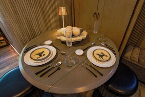 A round dining table set for two with plates featuring a giraffe design, a clear glass, and a bowl of bread. - Mid-Century Modern Chateau du Coach House (Iowa City)