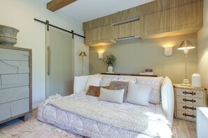 A bedroom with a bed, bedside tables, a wardrobe, and a wall-mounted air conditioning unit. - Mid-Century Modern Chateau du Coach House (Iowa City)