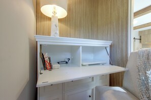 A white desk with a lamp, a chair, and a wooden panel wall. - Mid-Century Modern Chateau du Coach House (Iowa City)