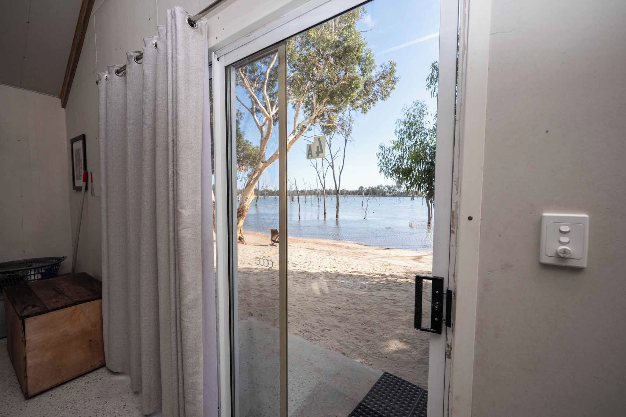 A room with a sliding glass door leading to a beach.