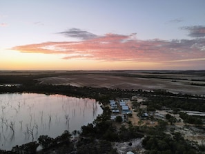 A rural landscape with a body of water, fields, and a small settlement with buildings.