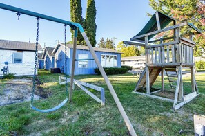 Ein Spielplatz mit Schaukeln und einem hölzernen Spielhäuschen.