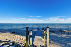 A wooden beach walkway leading to the ocean with beach chairs and a boat. - Yard w/ Lake Views! Quaint Tawas City Escape (Tawas City)