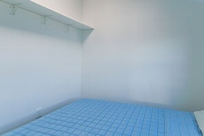 Ein Zimmer mit einem Einzelbett, einer weißen Wand und einer weißen Decke.