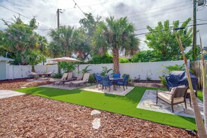 A backyard with artificial grass, a patio area with a table and chairs, and a hammock. - Walk to the Beach! Bright Cape Canaveral Apt (Cape Canaveral)
