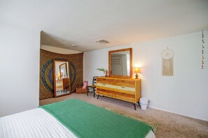 A bedroom with a bed, a dresser, a mirror, and a wall tapestry. - Walk to the Beach! Bright Cape Canaveral Apt (Cape Canaveral)
