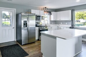 A modern kitchen with stainless steel appliances, a central island, and a view of the outdoors. - Lakefront Tawas City Gem w/ Gazebo & Beach Access (Tawas City)