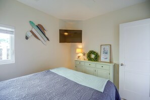 Ein Schlafzimmer mit Bett, Kommode, Fernseher und einer Tür.