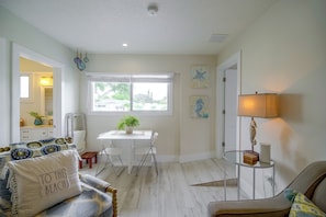 A bright room with a white ceiling, a dining table with chairs, a sofa, and a lamp. - Cape Canaveral Getaway w/ Pool - Walk to Beach (Cape Canaveral)
