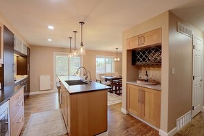 A modern kitchen with a central island, wooden cabinets, and pendant lighting. - Cherry Creek Reservoir Trail Access On-Site! (Englewood)