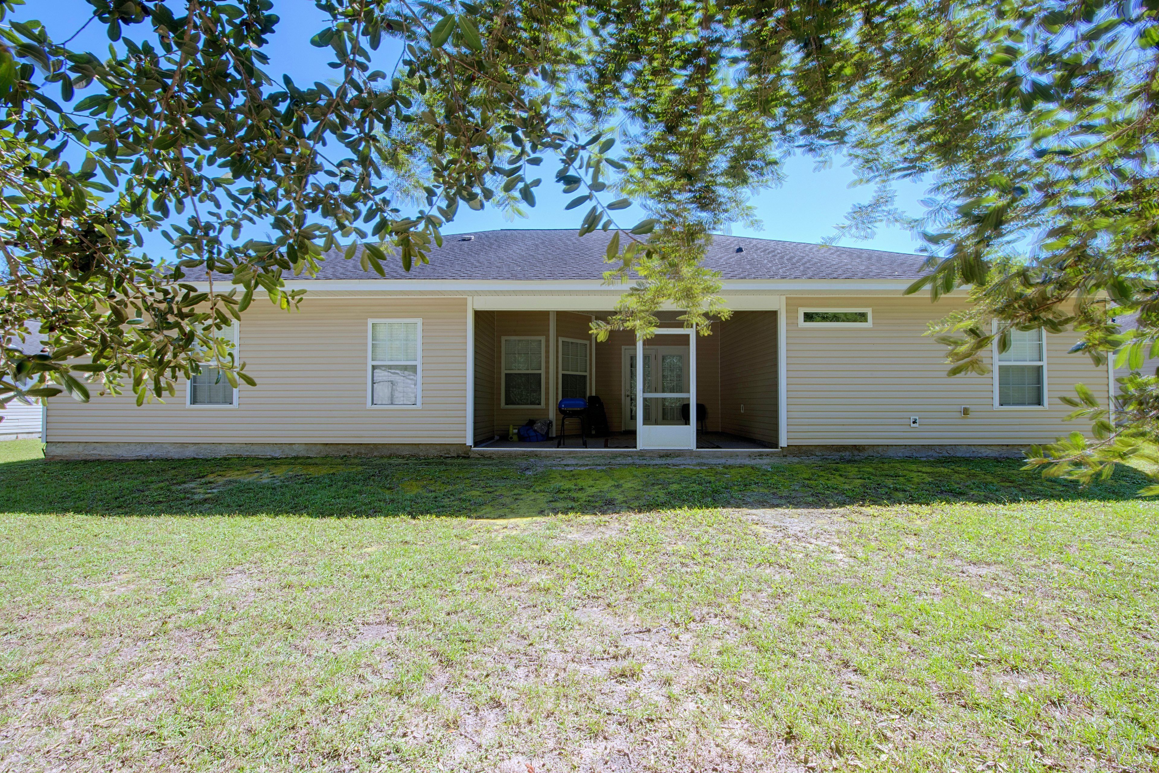 Rear exterior view of the house featuring the screened-in porch and spacious lawn.