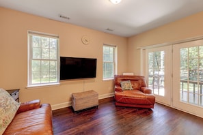 A living room with a flat-screen TV, leather sofa, and a wicker ottoman. - Quiet Horse Farm Hideaway Near Downtown Aiken (Aiken)