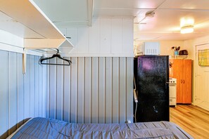 A compact room with a bed, a refrigerator, and a wooden cabinet. - Quaint Couple’s Unit w/ Lake Access in Tawas City (Tawas City)