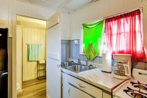 A compact kitchen with a sink, a coffee maker, and a stove. - Quaint Couple’s Unit w/ Lake Access in Tawas City (Tawas City)