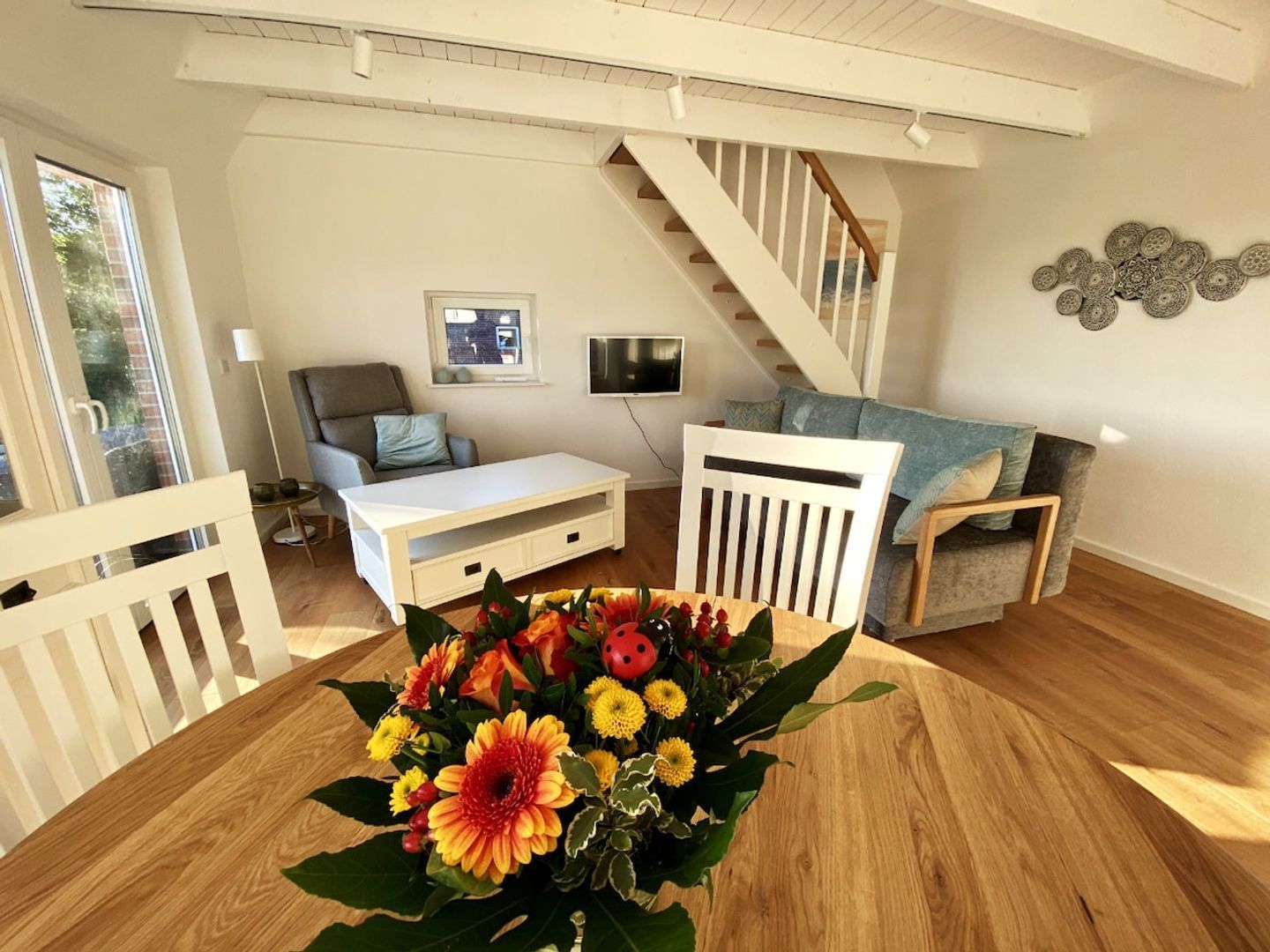 A living room with a white sofa, a coffee table, and a staircase.