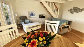 A living room with a white sofa, a coffee table, and a staircase.