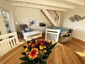 Ett vardagsrum med en vit soffa, ett soffbord och en trappa.