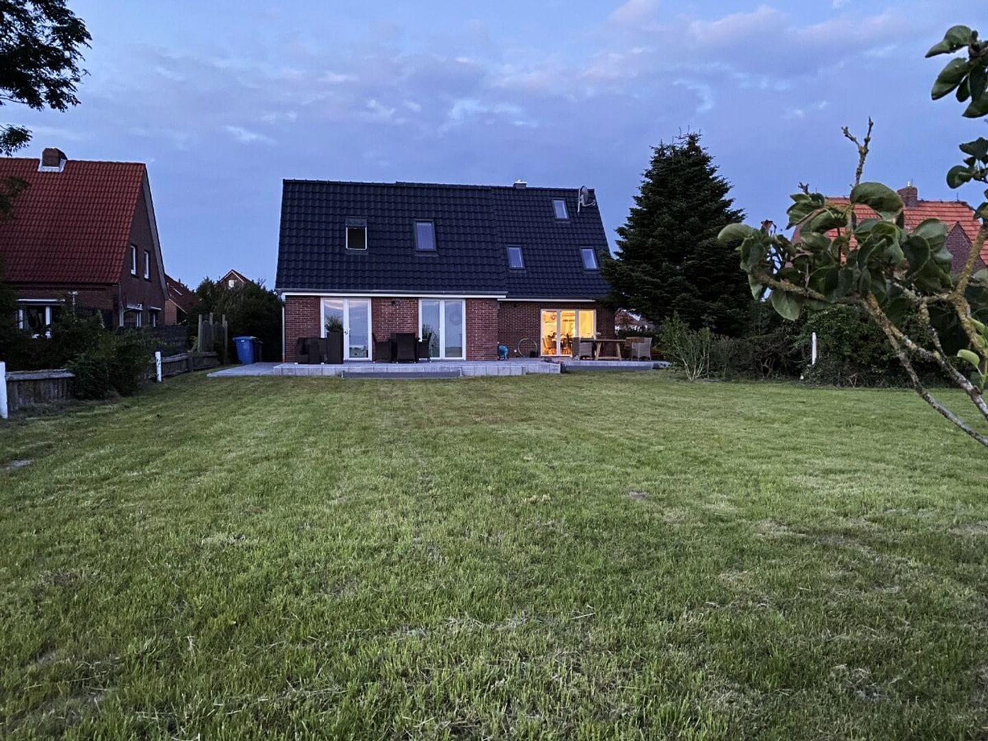A residential house with a sloped roof, a front porch, and a well-maintained lawn.
