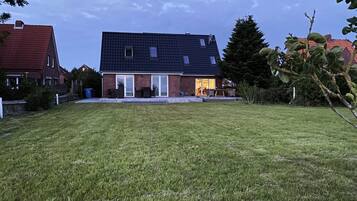 A residential house with a sloped roof, a front porch, and a well-maintained lawn.
