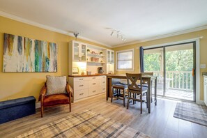 A room with a dining table, chairs, a sofa, a cabinet with glass doors, and a painting on the wall. - Lake Lure Mtn Getaway w/ Private Balcony (Lake Lure)