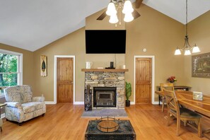 A living room with a fireplace, wooden furniture, a television, and a dining area. - 5 Acres, Screened Porch! West Union Farmhouse (West Union)