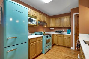 A kitchen with a turquoise refrigerator, wooden cabinets, a microwave, a stove, and a toaster. - 5 Acres, Screened Porch! West Union Farmhouse (West Union)