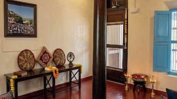 A room with a large wooden pillar, a framed picture on the wall, and a traditional decorative table.
