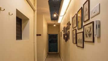 A hallway with patterned flooring, a blue door at the end, and framed pictures on the walls.