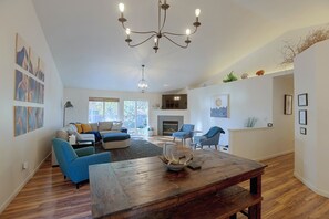 A spacious living room with a fireplace, a dining table, and a large window. - 3 Mi to Dtwn Bend: Private Hot Tub & Yard (Bend)