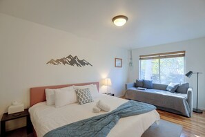 A bedroom with a bed, a sofa, a bedside table, a lamp, a wall decoration, and a window with a view. - 3 Mi to Dtwn Bend: Private Hot Tub & Yard (Bend)