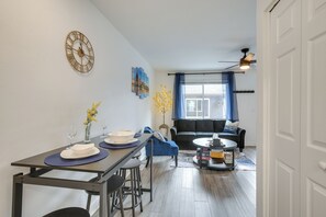 A modern living room with a sofa, a coffee table, and a dining area with a table set for two.